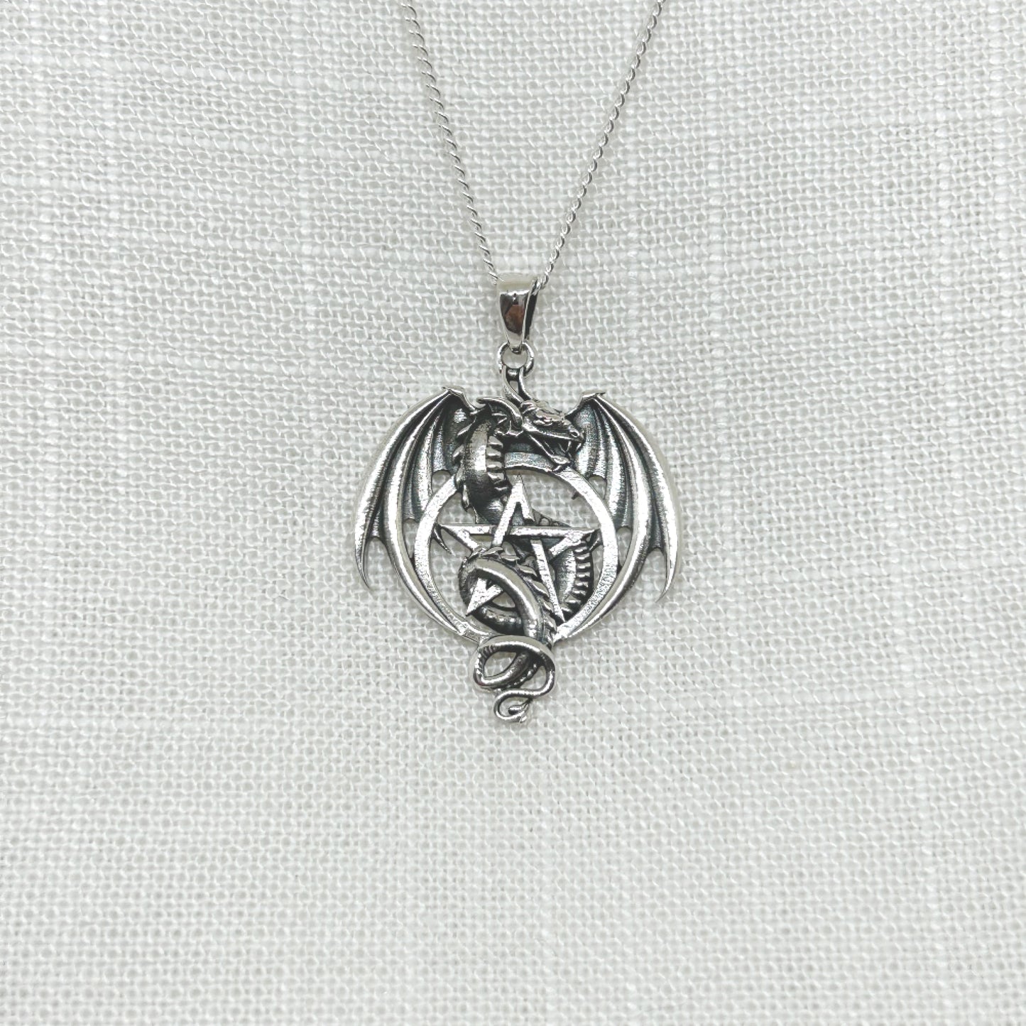This stunning .925 silver dragon entwines itself within a pentacle, while his wings are semi open. Approx 3.6cm long including the bale x 2.6cm wide. All pendants come supplied on an 20" Sterling Silver Curb Chain and are gift boxed.