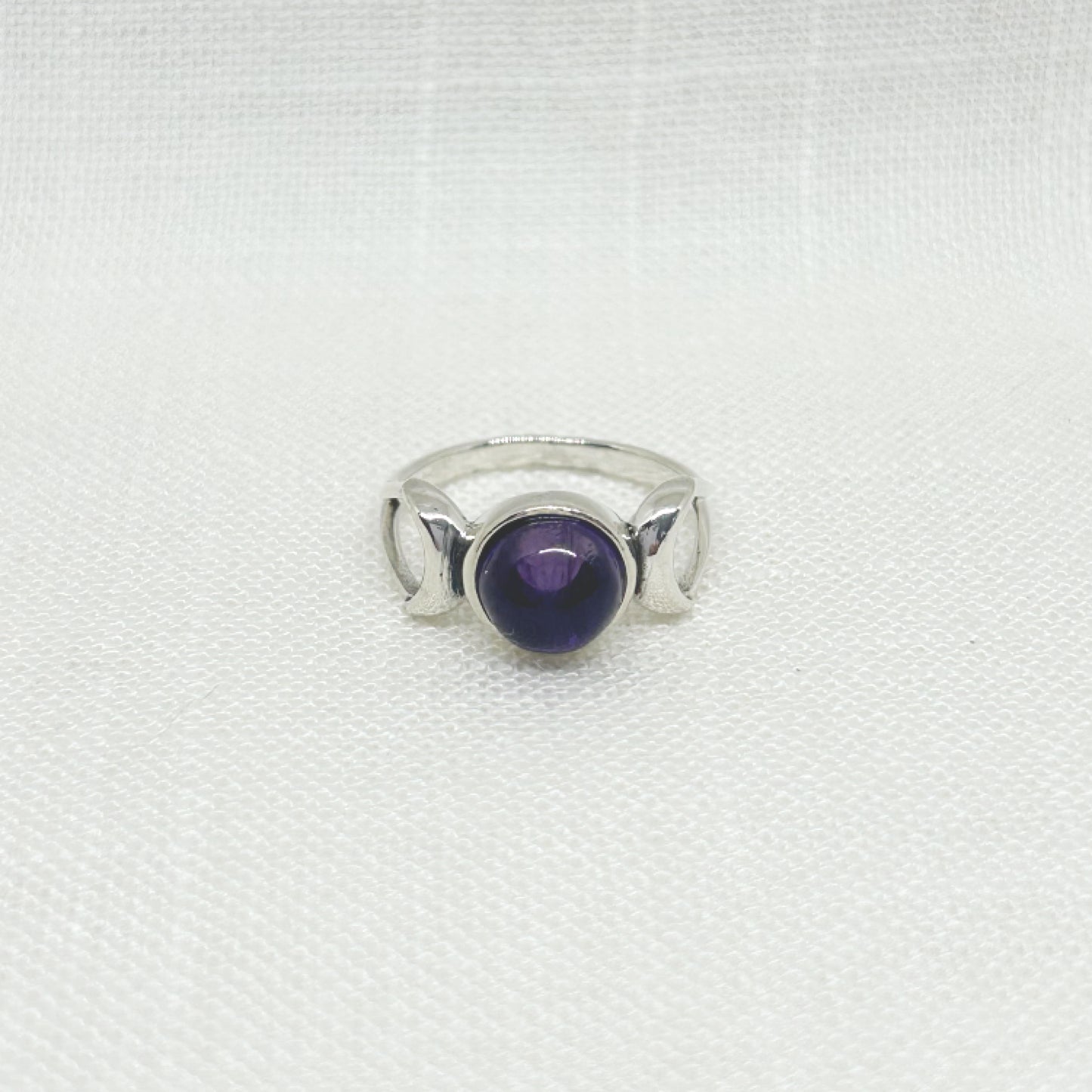 With a generous 0.8cm amethyst cabochon within the centre moon and a crescent moon either side, this beautiful triple moon ring represents the Goddess in her 3 main phases: waxing, full and waning. This ring is set in .925 silver and is hallmarked. All jewellery comes gift boxed.