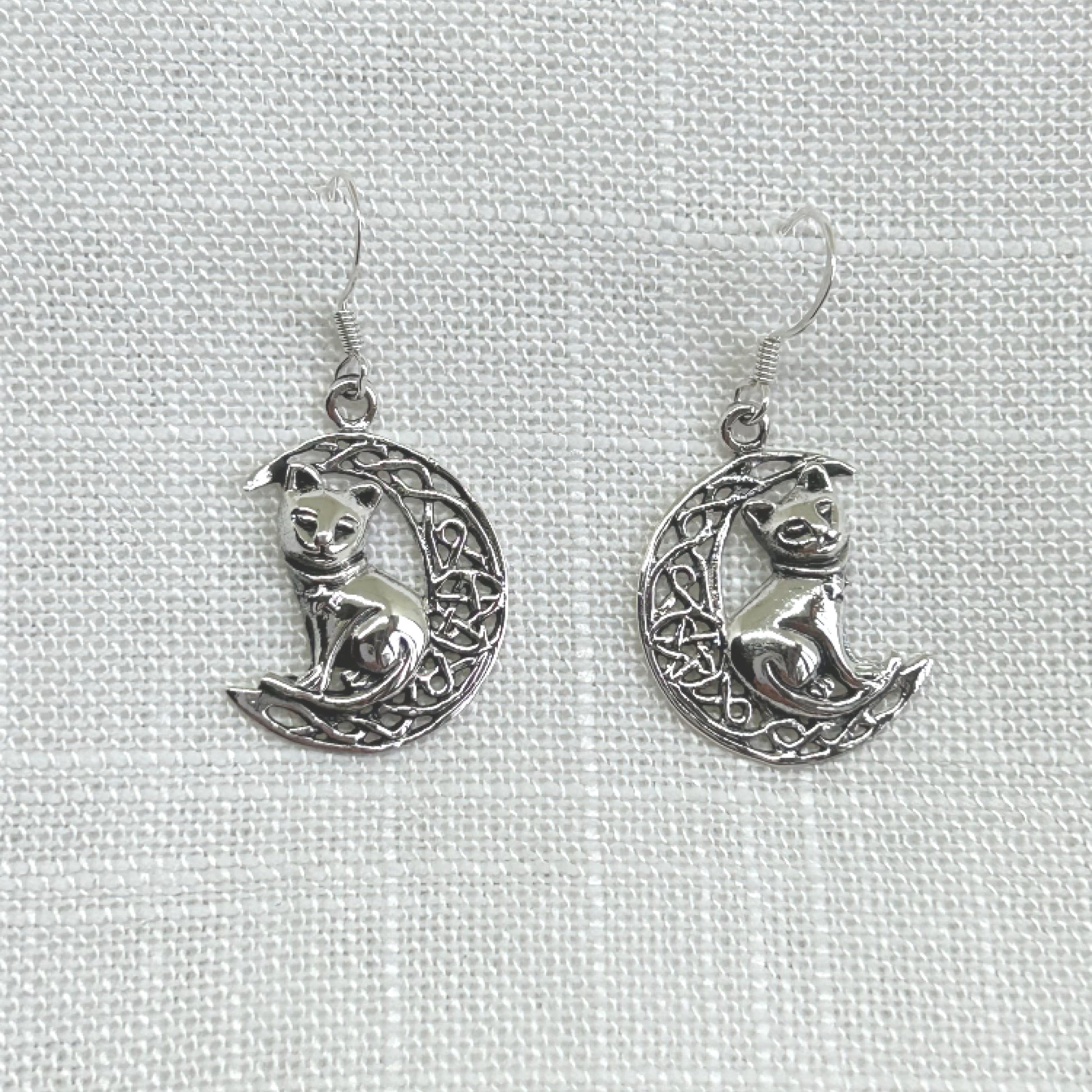Delicately crafted in 925 silver with a detailed cat and Celtic knot crescent moon, these earrings are sure to make a unique statement of wisdom, fate, and divination. It features an intricate Celtic knot style crescent moon with a pentacle within the centre and a cat sitting on the crescent. Size from top of hook is approximately 3.5cm by 1.8cm wide. Total weight of each earring is 1.9g. Matching necklace is available.