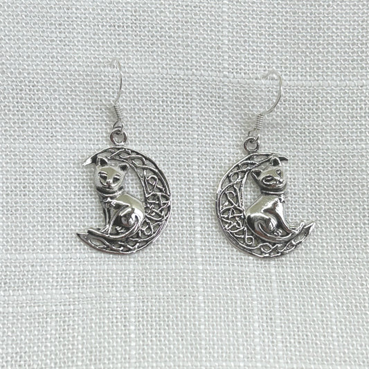 Delicately crafted in 925 silver with a detailed cat and Celtic knot crescent moon, these earrings are sure to make a unique statement of wisdom, fate, and divination. It features an intricate Celtic knot style crescent moon with a pentacle within the centre and a cat sitting on the crescent. Size from top of hook is approximately 3.5cm by 1.8cm wide. Total weight of each earring is 1.9g. Matching necklace is available.