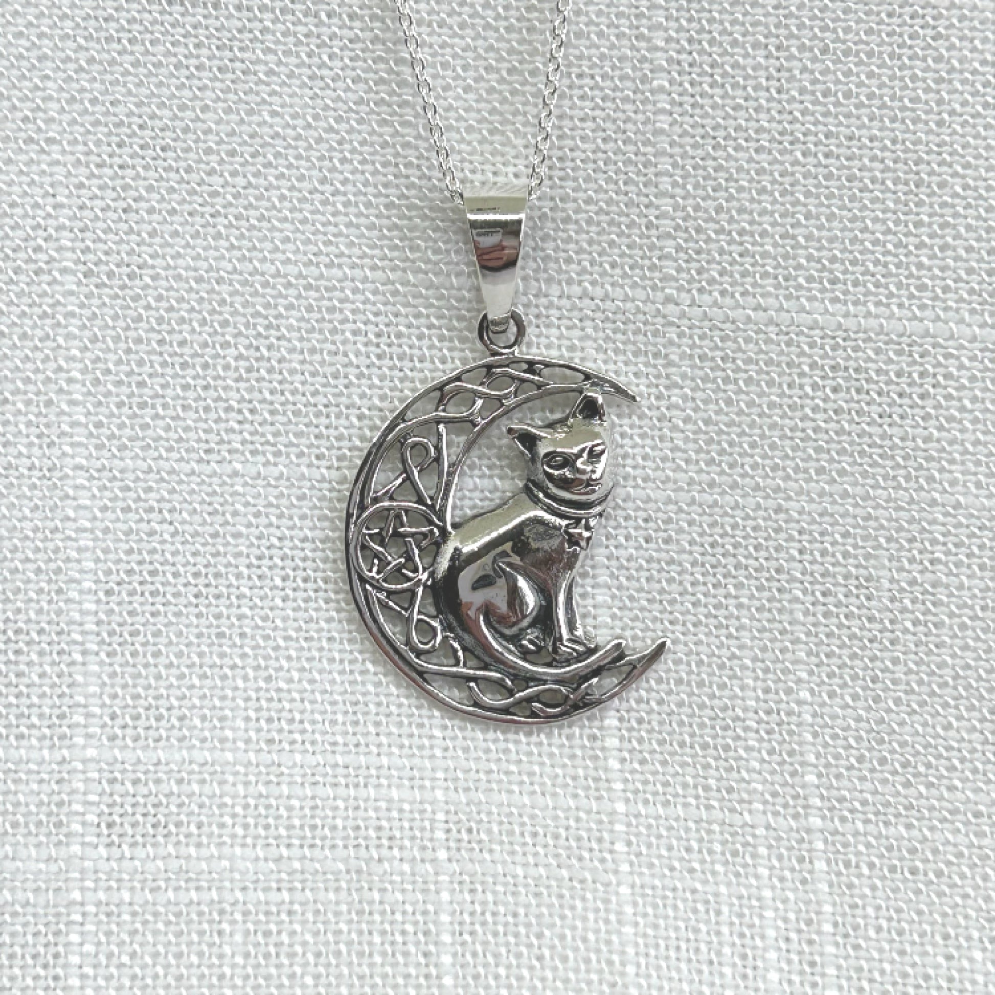 Delicately crafted in 925 silver with a detailed cat and moon, this necklace is sure to make a unique statement of wisdom, fate, and divination. It features an intricate Celtic knot style crescent moon with a pentacle within the centre and a cat sitting on the crescent. The pendant is approximately 3.6cm long including the bale by 2.3cm wide. Total weight is 5.9g. Matching earrings are also available.