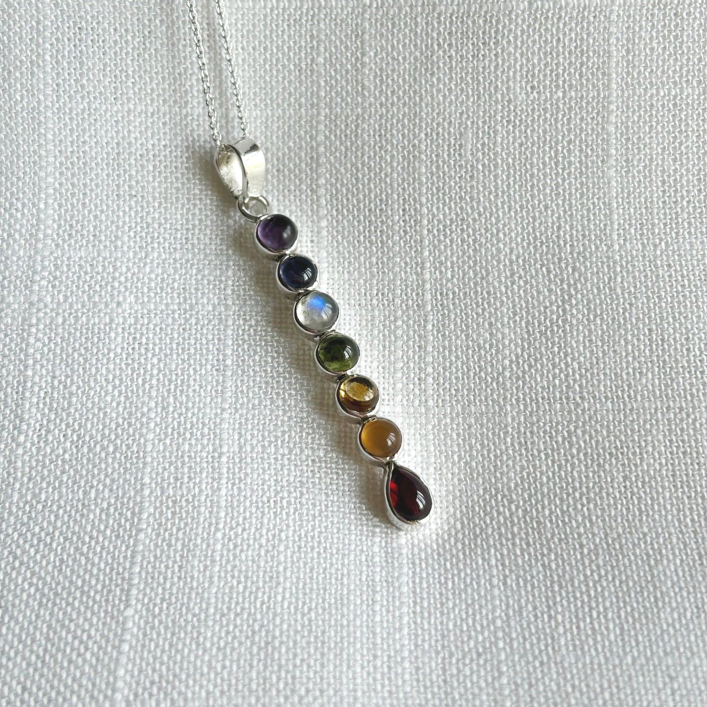 This smaller genuine gemstone pendant necklace includes all the essentials of the seven Chakras.   These multi coloured gemstones represent the colours of the energy centres within the body know as Chakra points.  Amethyst crown, Iolite third eye, Topaz throat, Peridot heart, Citrine solar plexus, Carnelian sacral and Garnet.  Size: 5.5cm Long including the bale x 0.5cm Wide. Pendant Weight is 3.8g  All pendants come supplied on a 20 inch sterling silver chain