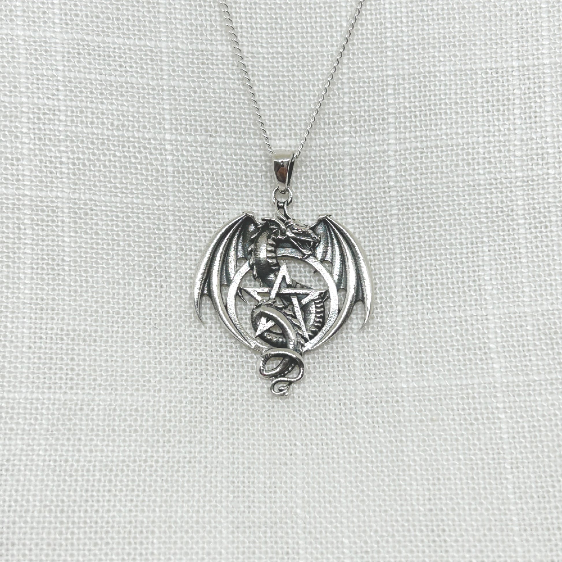 This stunning .925 silver dragon entwines itself within a pentacle, while his wings are semi open. Approx 3.6cm long including the bale x 2.6cm wide. All pendants come supplied on an 20" Sterling Silver Curb Chain and are gift boxed.