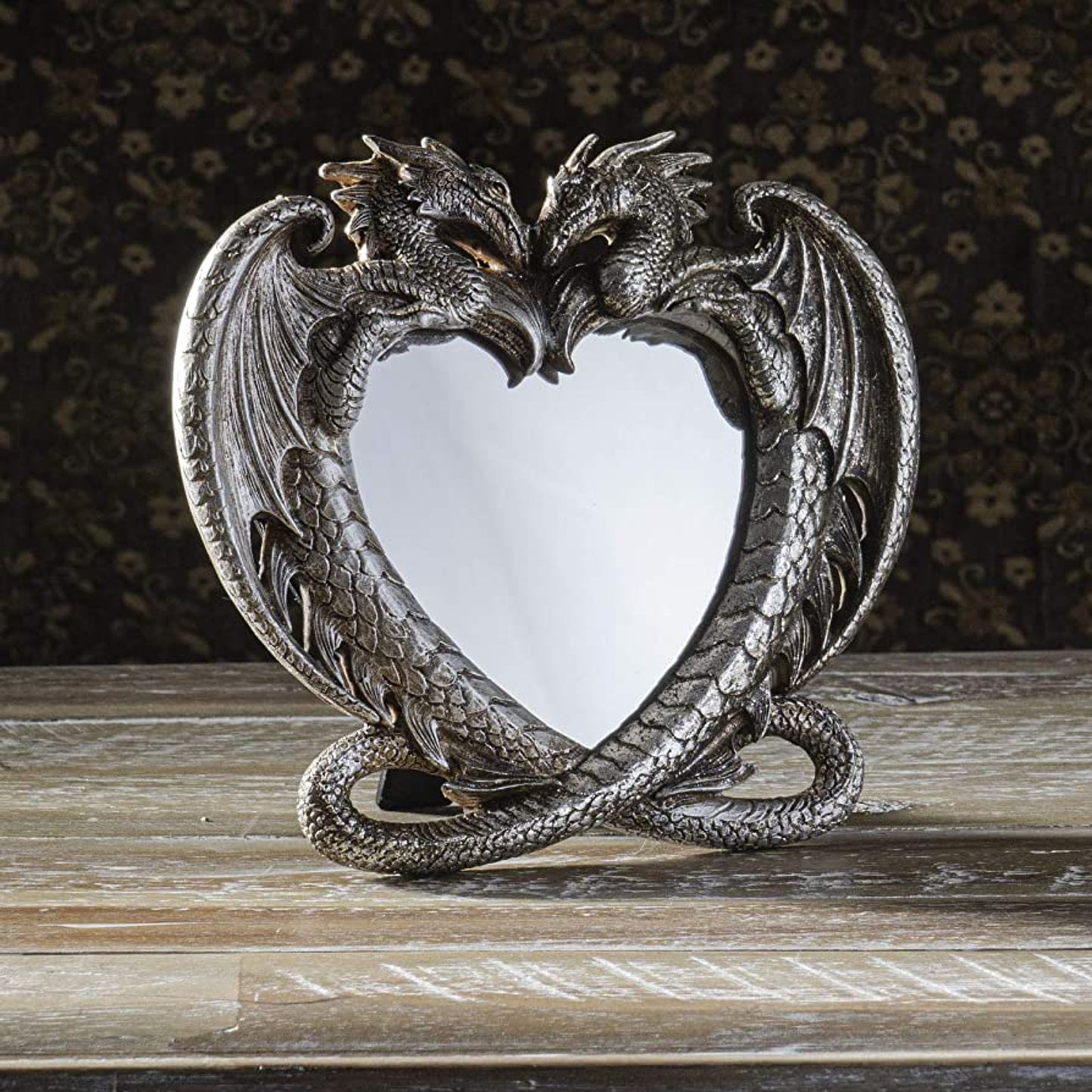 Conceived from primordial flames amidst the visions of the primeval divinities, this mirror has been summoned by fate to discover its ultimate soulmate.  An iconic symbol of adoration, this beautiful heart-shaped Dragon Mirror can be placed atop a surface or hung on a wall.  High quality resin hand finished in antique silver effect.