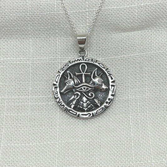 This .925 silver pendant features multiple symbols including an ankh, pyramid, Anubis and eye of Horus.
The oxidized background highlights the intricate details of both symbols, making this necklace a unique and eye-catching accessory.
The pendant is approximately 3.5cm long including the bale x 2.5cm wide x 1mm thick.
The pendant will come on a 20" sterling silver chain and arrive in a tarnish proof bag inside a gift box.