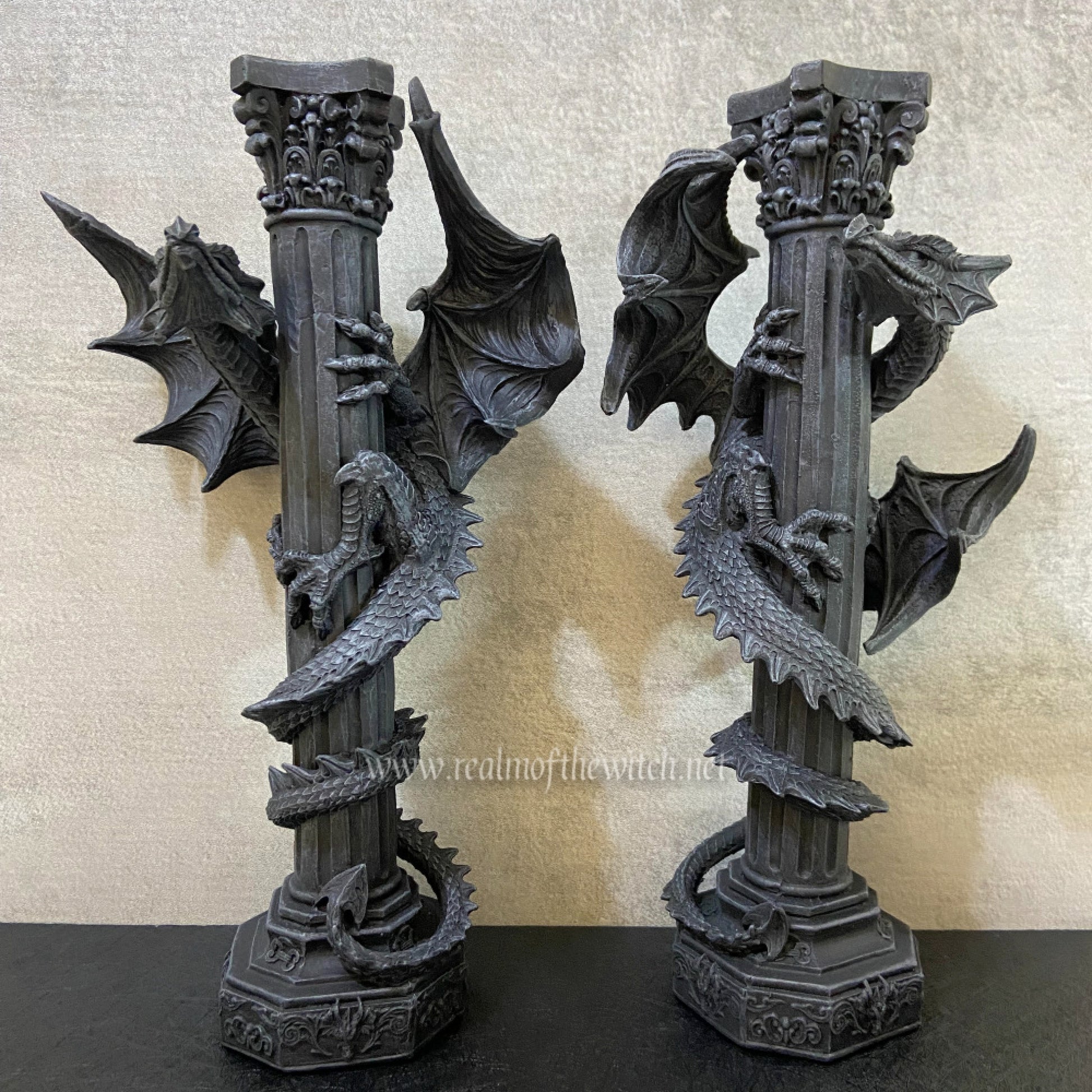 Ideal for the home of a fan of mythical creatures, this set of 2 candle holders expertly crafted from resin and hand painted offers a unique accent.  The dragon figures, against a pair of baroque columns, twist their bodies around the posts with wings spread wide.  Add a touch of atmosphere to any living or dining area - these eye-catching holders bring a subtle light and charm. 28cm tall