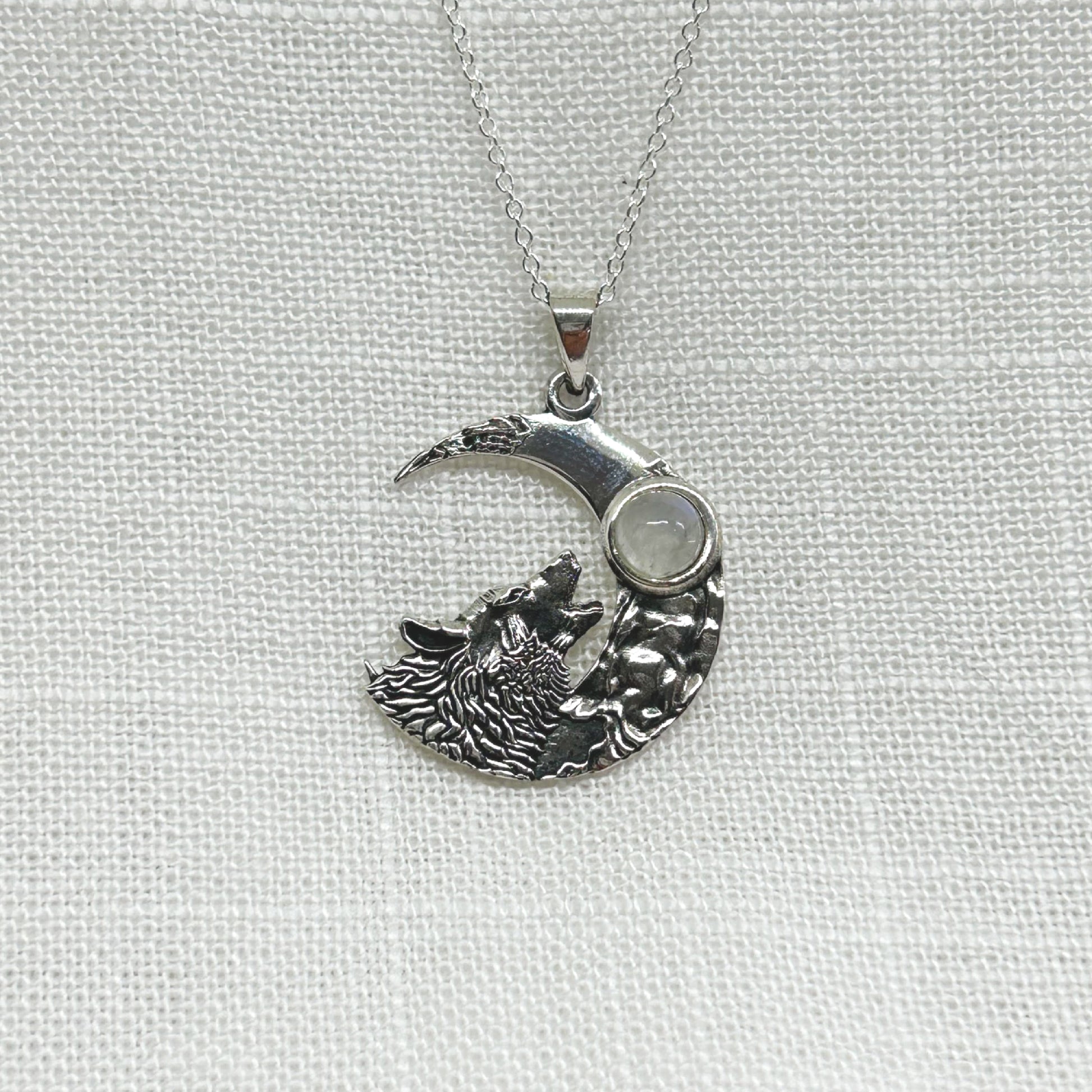 This highly polished silver necklace features a wolf howling at the moon with a rainbow moonstone cabochon. All pendants come supplied on an 20" Sterling Silver Curb Chain and are gift boxed. ﻿Also available with an Amethyst cabochon Size approx: W: 2.3cm x H: 3.3cm including bale