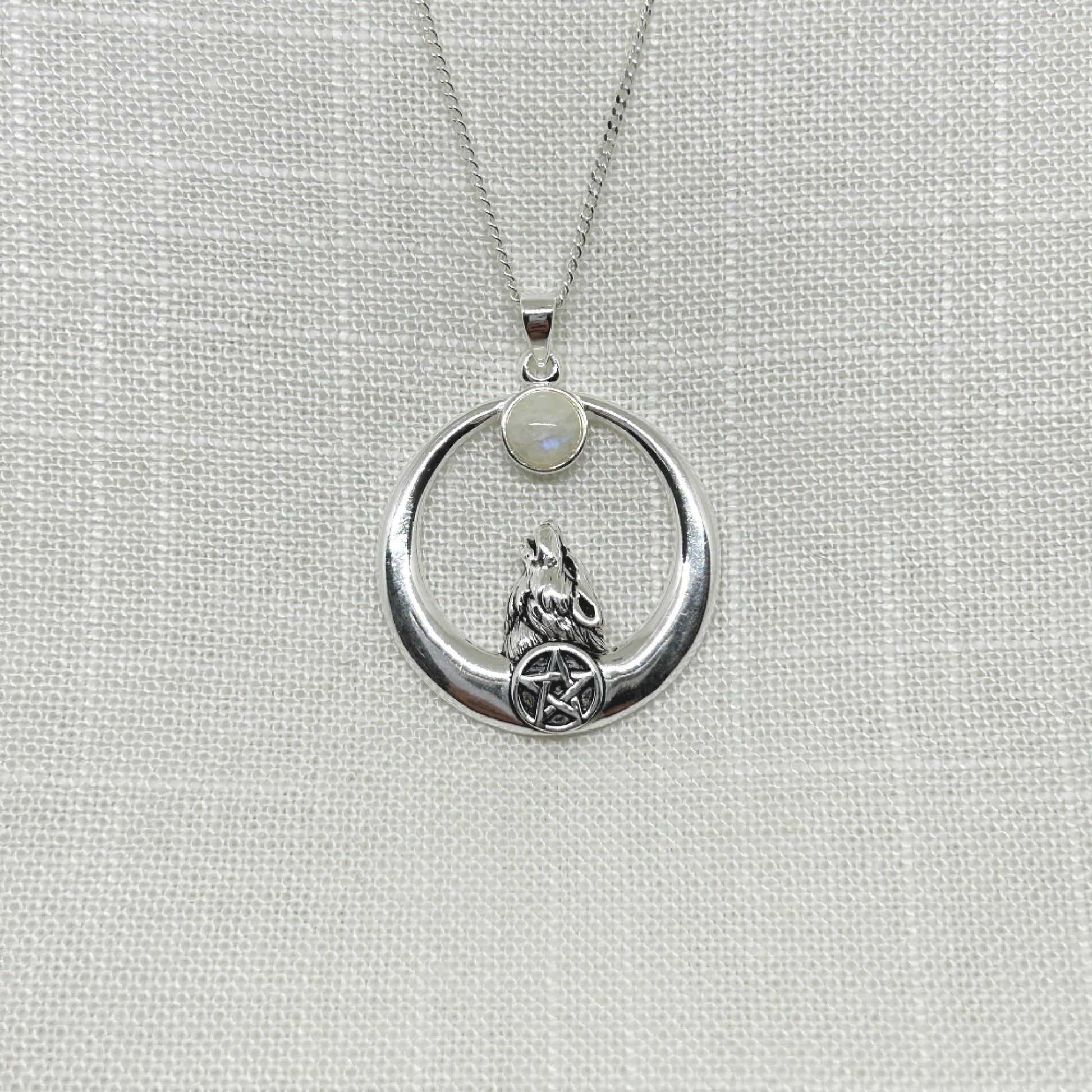 A lone wolf has his head tilted back, gazing up to the full moon, set with a moonstone. Below his neck is a pentacle symbol. Pendant is 3.75cm high and has been slightly oxidized to enhance the detail. It comes complete with a 20 inch silver cable chain.