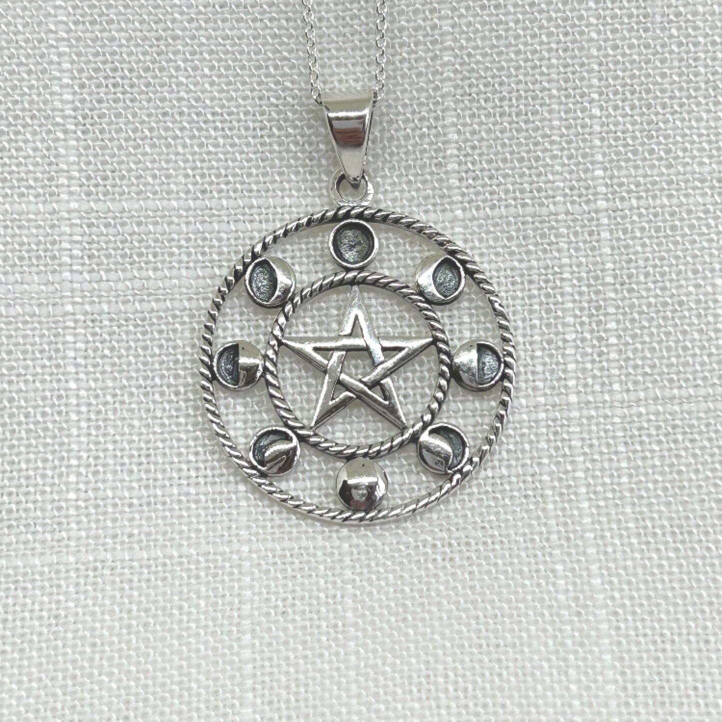 Set in 925 silver, this beautiful pendant shows the eight different phases of the moon that have been followed by our ancestors since the beginning of time. Within the centre of the pendant is a pentagram symbolising the 5 essences of life: Earth, Air, Fire, Water and Spirit. The size of this pendant is approximately 3.9cm long including the bale by 3cm wide. Total weight is 7.5g