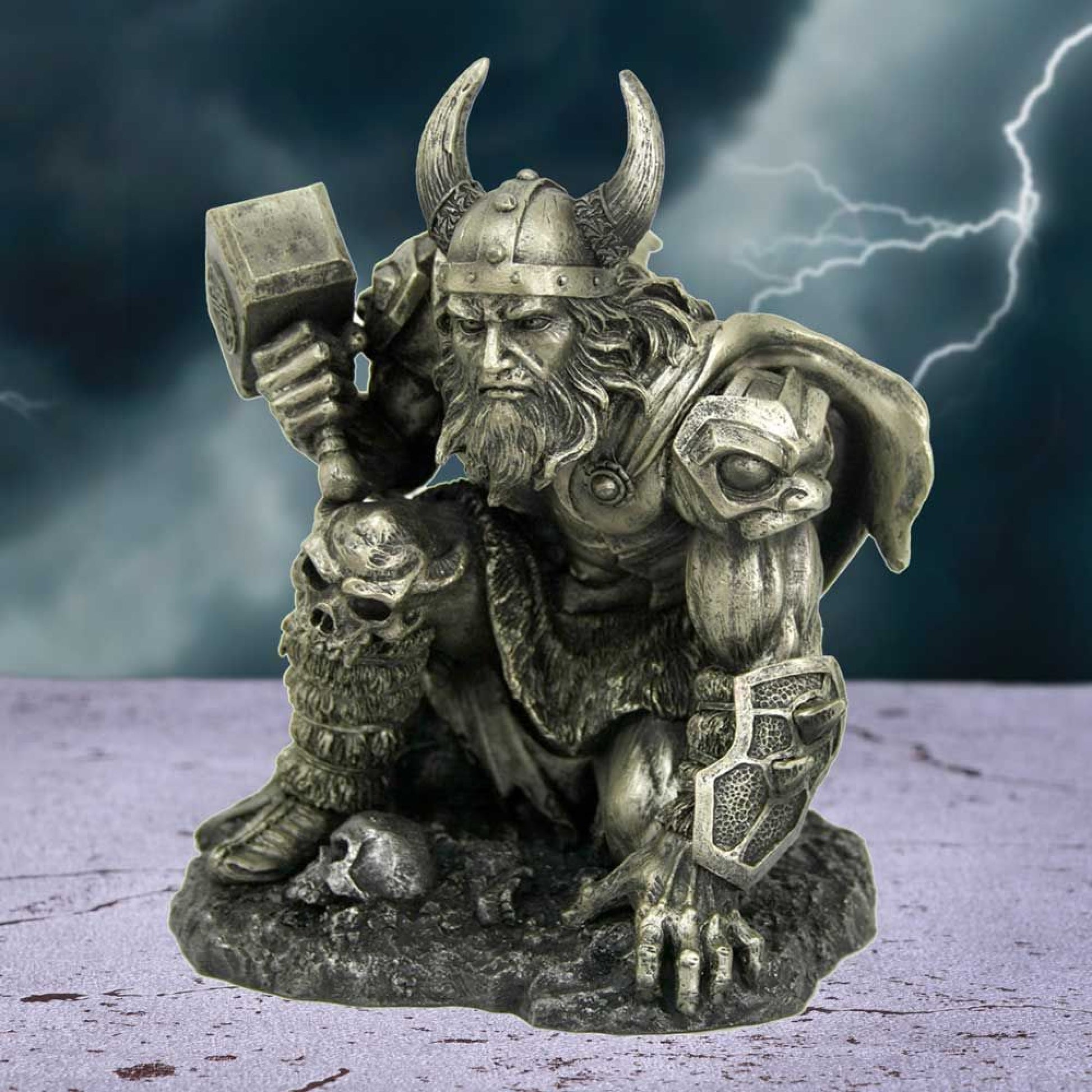 Rising from the ground, Thor, son of Odin, looks ahead of him with grim determination. Pushing himself up with his left hand, he clasps his legendary hammer, Mjolnir in his right. His armour is adorned with skulls, cape billowing behind him in the wind. On the black rocky ground by his foot, there is a single human skull.