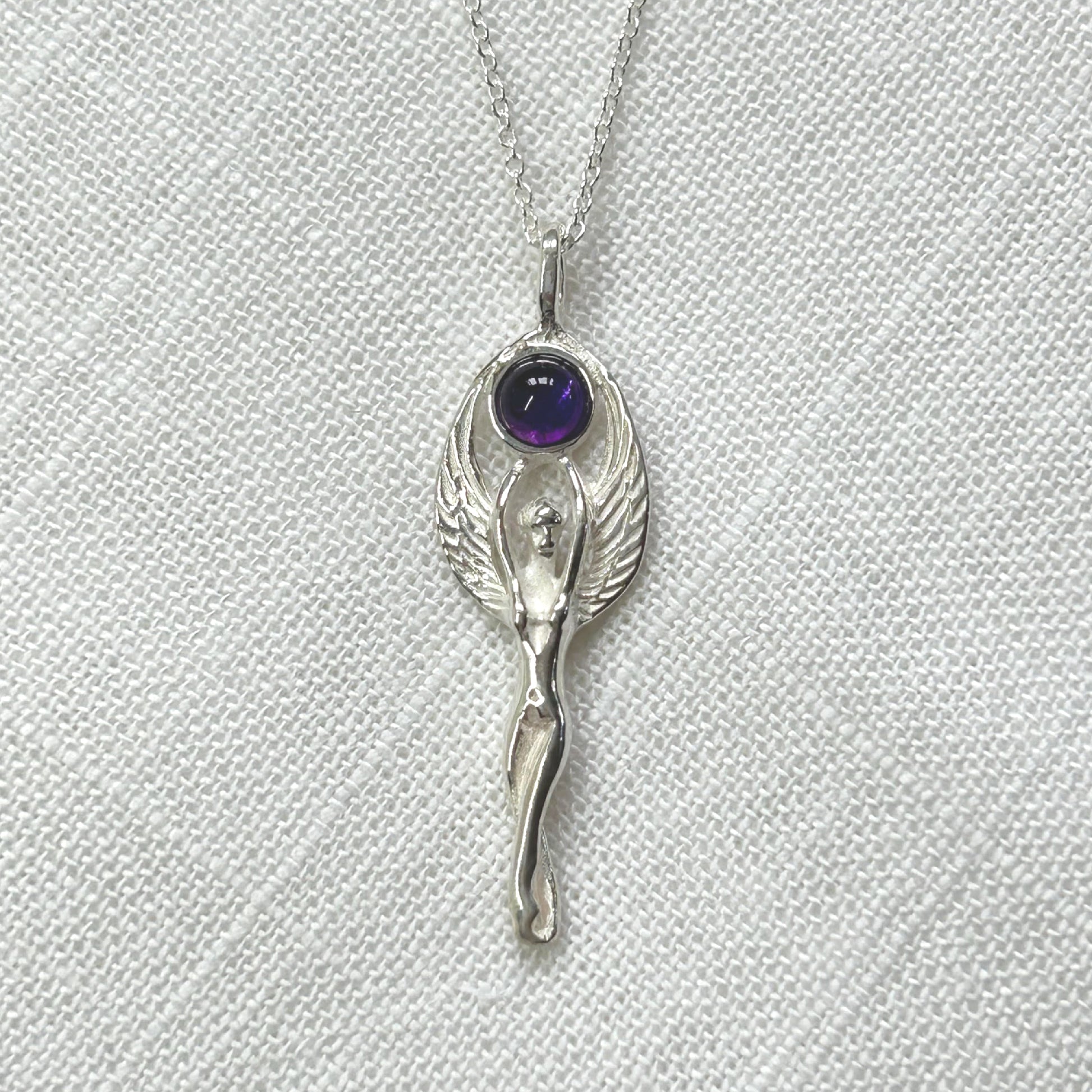 Set in 925 silver, this gorgeous Goddess reaches her arms above her head to hold an amethyst cabochon. Her wings then envelope the outside of the gemstone. She measures 4cm long (inc bale) x 1.3cm wide. All pendants come supplied on a 20" Sterling Silver Curb Chain and are gift boxed. This necklace is also available with a Rainbow Moonstone cabochon.