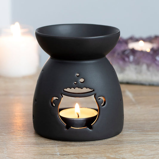 This black ceramic oil burner features a cut out bubbling cauldron design and a cool, matt finish. Compatible with both fragrance oil and wax and perfect for Halloween or spooky decor! Part of the ever popular Black Magic Collection. These burners are compatible with wax melts and fragrance oils (sold separately).  Dimensions: H: 10cm x W: 9cm x D: 9cm  Material: Ceramic