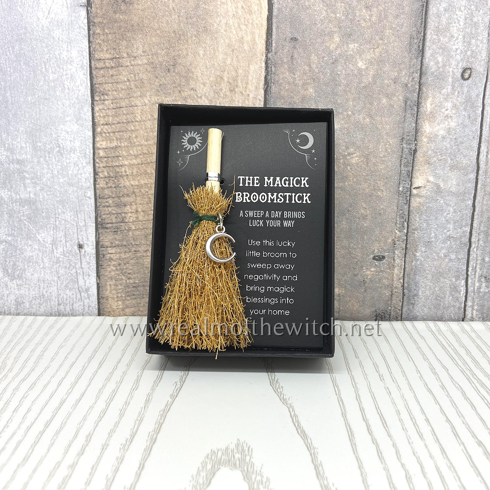 Attract luck and positive energy with this mini magic broomstick. Perfect in size for using on a mini altar, displaying on kitchen shelf, keeping at a desk, or taking on the go for extra positivity. Features text that reads, 'A sweep a day brings luck your way'. Use this lucky little broom to sweep away negativity and bring magick blessings into your home' and a silver tone crescent moon charm. Presented in a black box perfect for display and gifting. 