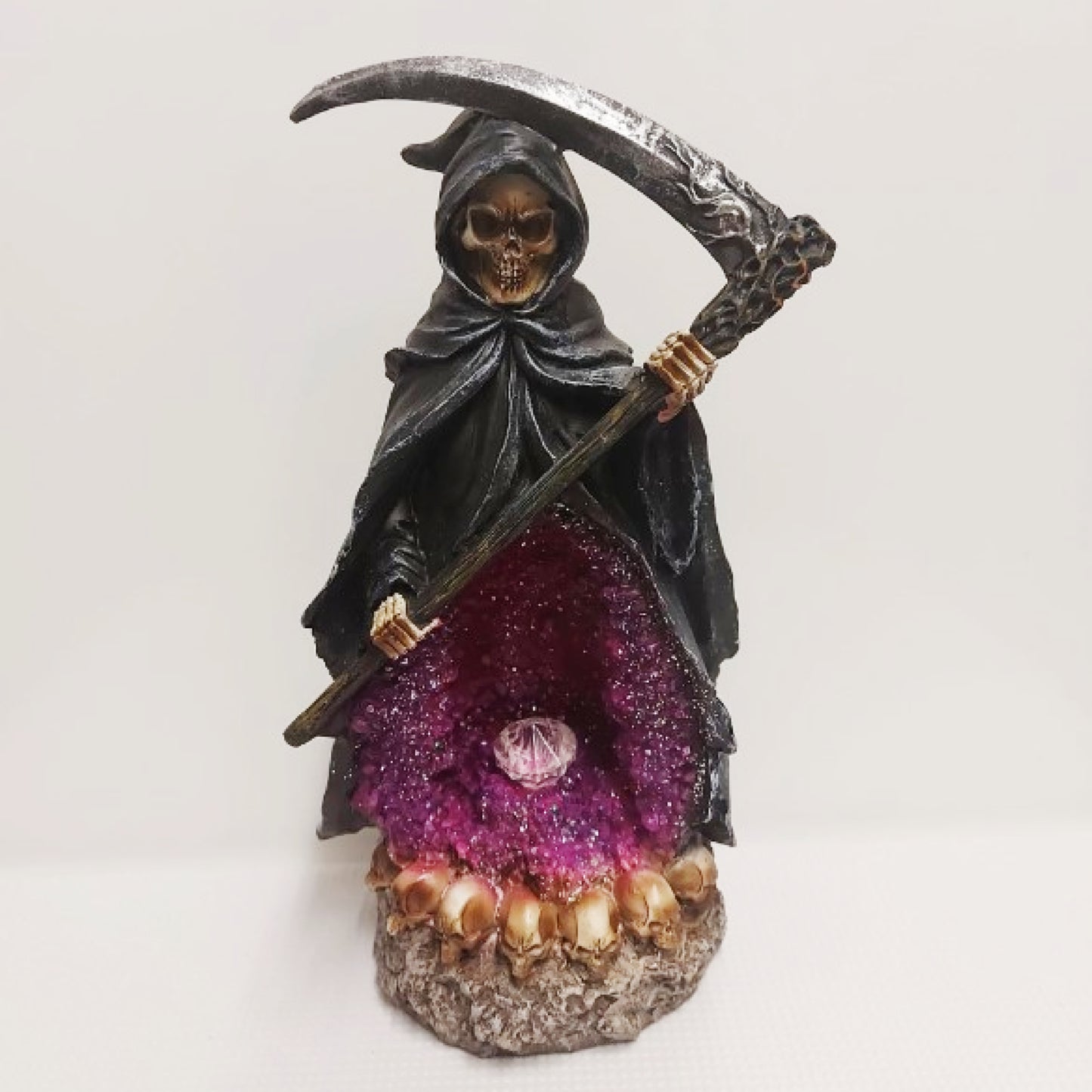This captivating backflow burner features a foreboding grim reaper and his scythe. A clear resin crystal lights up while smoke gently cascades through a glimmering crystal cave. Powered by an on off switch and 2 AA batteries. 26cm high