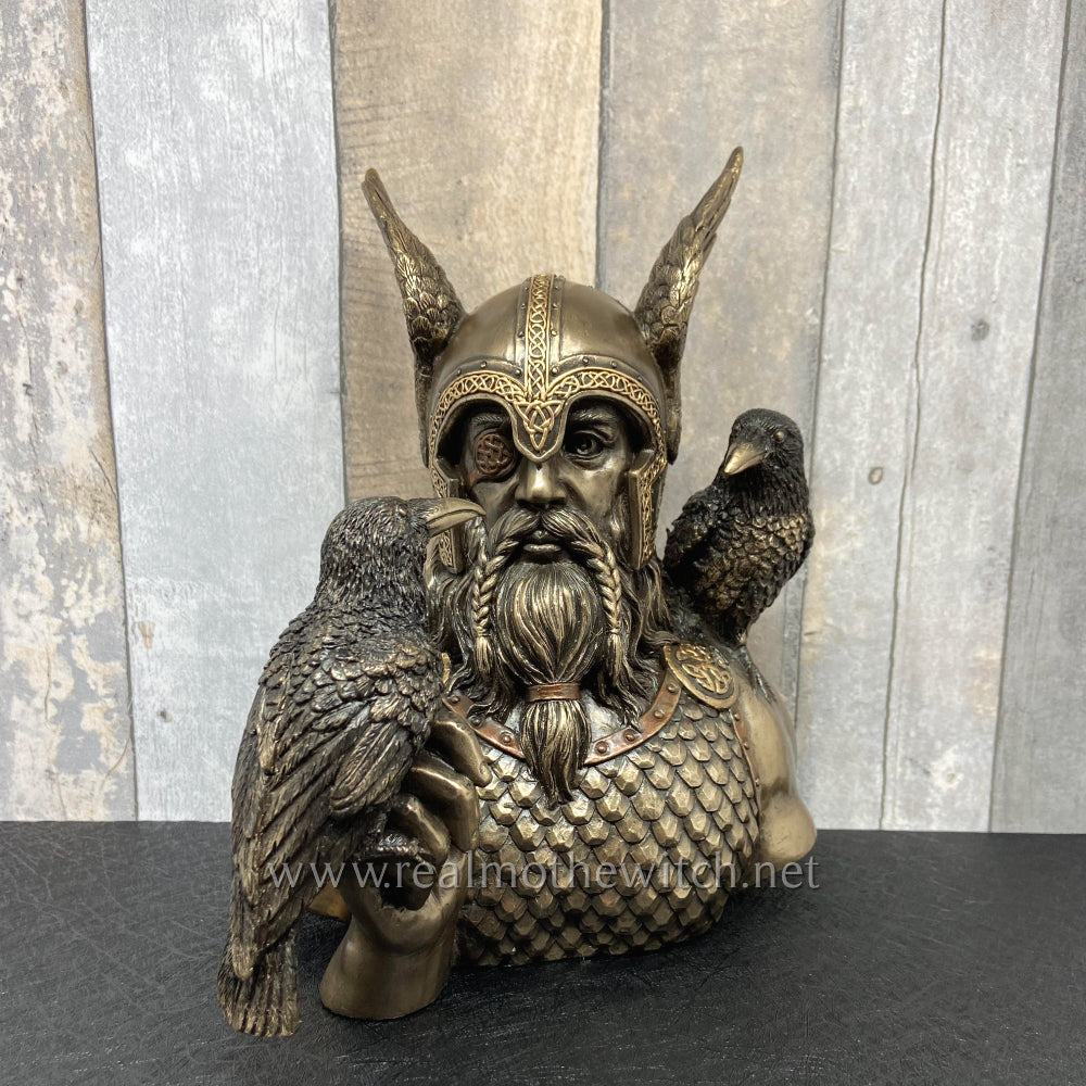 Norse God Odin Bust, featuring his two Raven messengers. This portrayal of Odin shows him wearing a winged helm and armoured chest piece. His right hand raised becomes a perch for one of his raven companions. The other sits on his shoulder. These two ravens are Huginn (thought) and Muninn (mind)