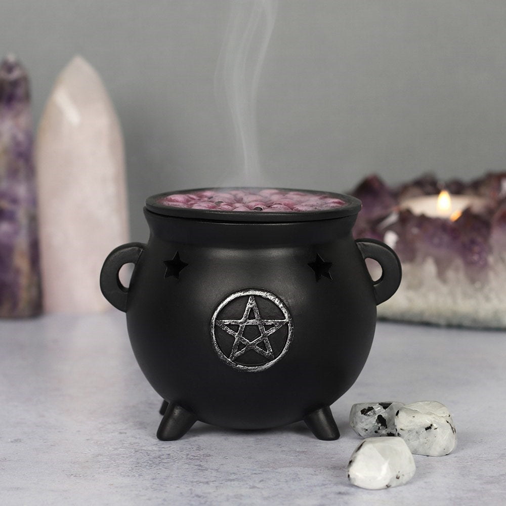 Place your favourite scented incense cones in this magical cauldron, pop the lid on and watch the smoke rise up like a steaming hot brew! Accented by cut out stars and a distressed silver-effect pentagram design, with a removable 'bubbling' brew top.  Size: H: 8cm x W: 10cm x D: 9cm