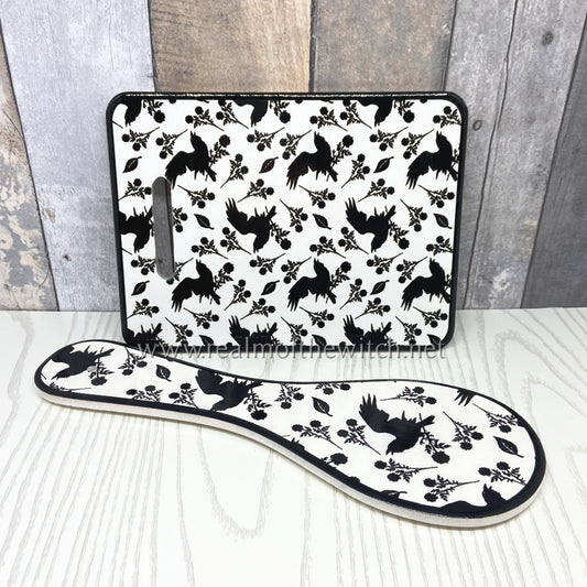 A beautiful trivet and spoon rest decorated in the elegant Alchemy raven and rose design. Both the trivet/cheese/chopping board and the spoon rest are fully functional kitchen essentials and will make a beautiful addition to your kitchen either by the cooker or hanging on the wall. 