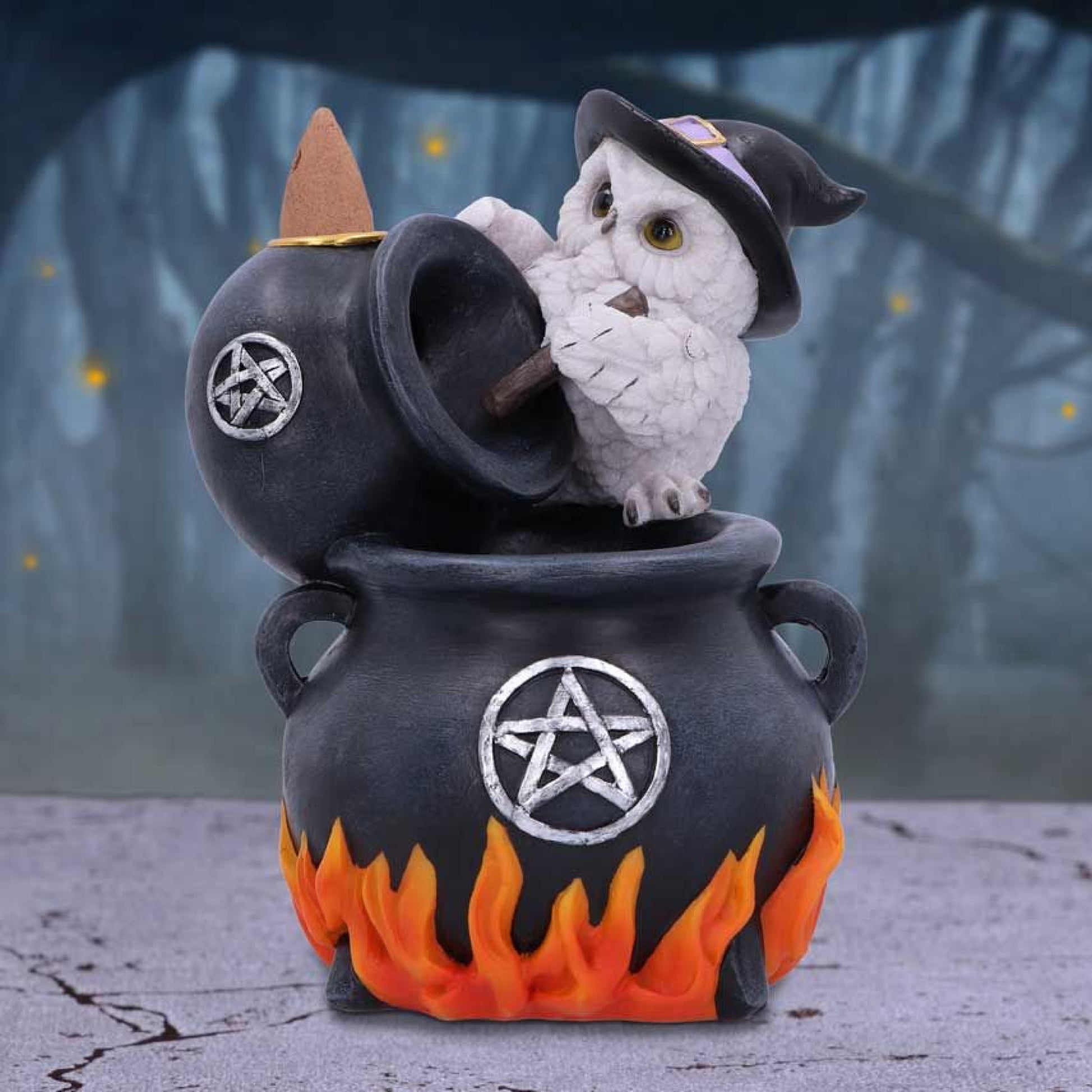 Standing atop a cauldron with a pointed black witch's hat on its head, this owl is conjuring a spell.  Whilst a metal tray rests on top of the black bowl, ready to accommodate your favourite backflow incense cones, which once lit will create smoke that flows into the cauldron from the bowl.  Cast in the finest resin before being expertly hand painted, this incense burner is perfect for any alternative home or witchcraft collection. 17cm