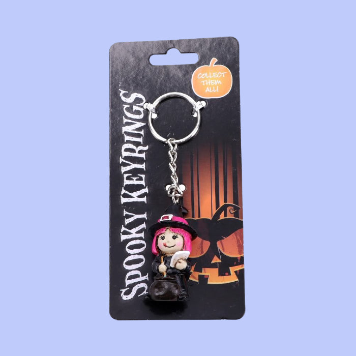 This Spooky Witch Keyring is the perfect accessory to add a touch of magic to any look.  Its detailed design captures the spirit of the season without sacrificing style.  This small pink haired Witch stands next to a bubbling cauldron, making another batch of her most spooktacular brew.  She stirs the pot while reading the incantation within her grimoire.  5cm