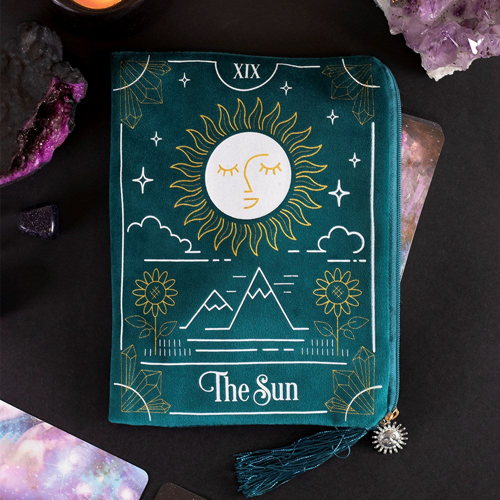 This velvet zipper pouch is the perfect place to keep tarot decks, crystals, beauty products and other treasures. Features a stunning white and gold sun tarot card illustration on the front and a matching tassel and gold sun charm on the zipper. Size: H: 15cm x W: 20cm x D: 0.75cm Material: Polyester