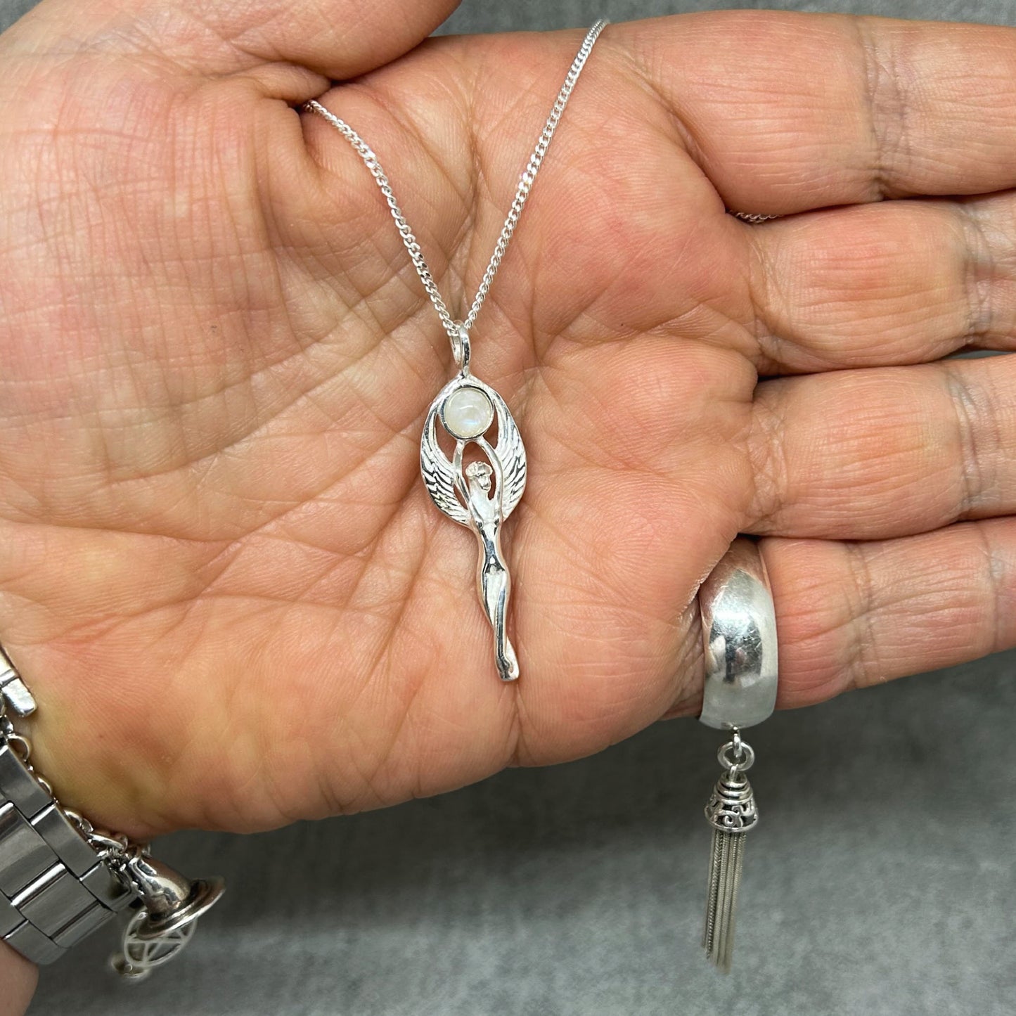 Set in 925 silver, this gorgeous Goddess reaches her arms above her head to hold a rainbow moonstone cabochon.  Her wings envelope the outside of the gemstone.  She measures 4cm long (inc bale) x 1.3cm wide.   All pendants come supplied on a 20" Sterling Silver Curb Chain arriving in a tarnish proof bag inside a gift box. 