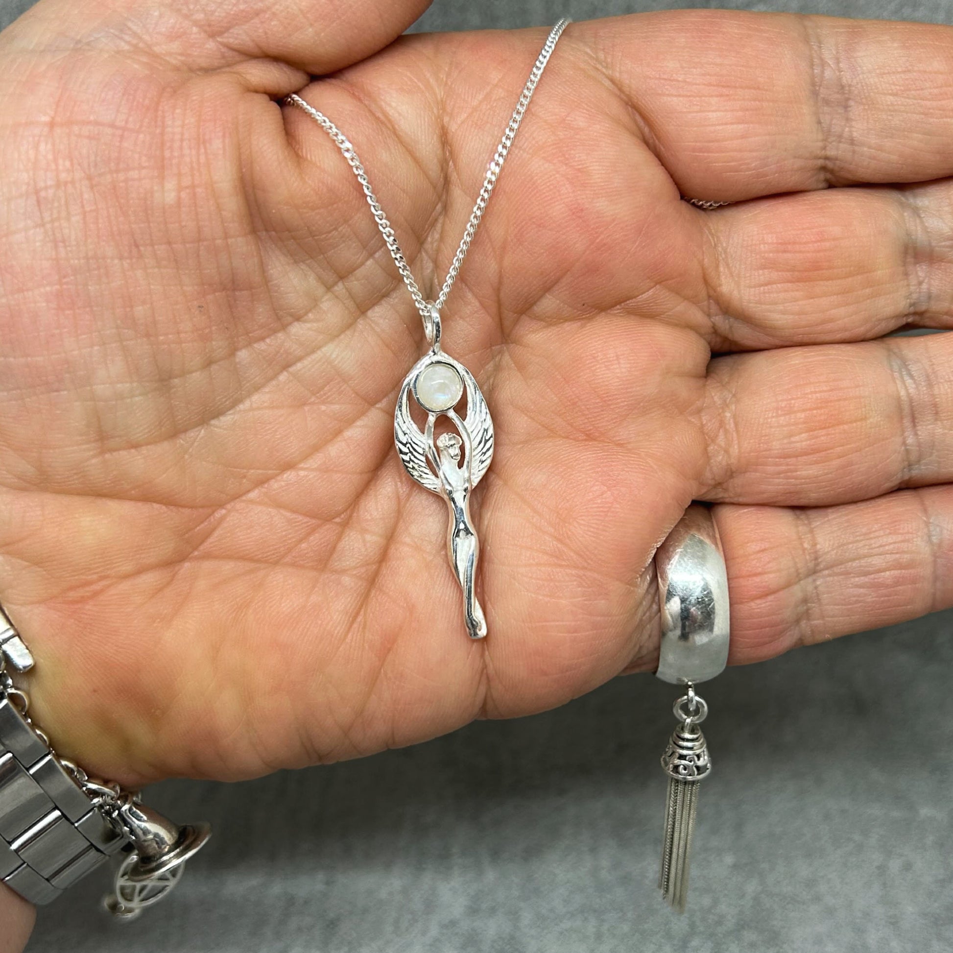 Set in 925 silver, this gorgeous Goddess reaches her arms above her head to hold a rainbow moonstone cabochon.  Her wings envelope the outside of the gemstone.  She measures 4cm long (inc bale) x 1.3cm wide.   All pendants come supplied on a 20" Sterling Silver Curb Chain arriving in a tarnish proof bag inside a gift box. 