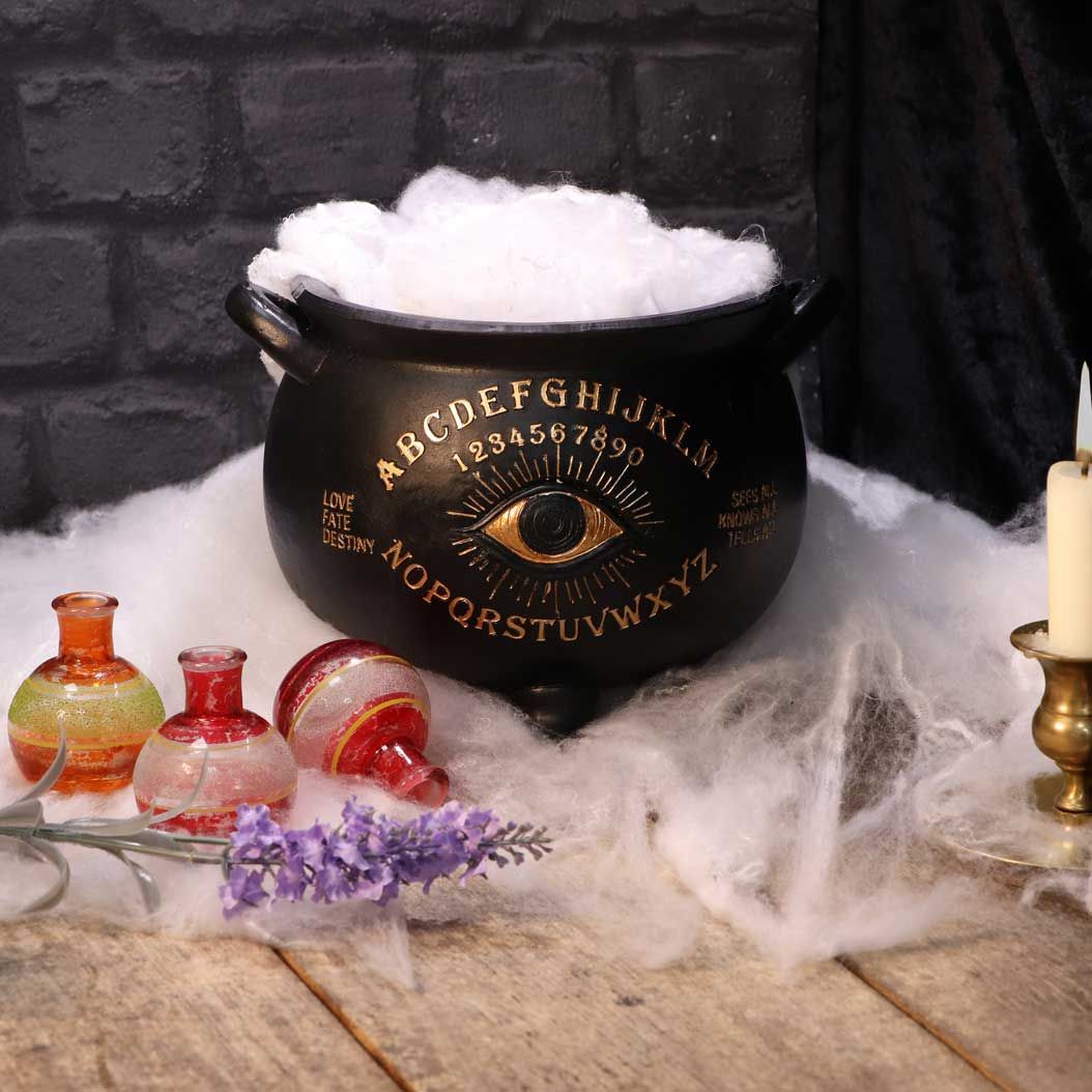 With a wide opening at the top, ready to fill with your treasured crystals and trinkets, this cauldron has a matte black finish and features a golden all-seeing eye at the centre. Emblazoned in Ouija Board lettering and numbers, the cauldron has the words 'Love, Fate, Destiny' and 'Sees all, Knows all, Tells all' flanking the Eye. Cast in the finest resin, this piece would make the perfect addition to any altar or living space.  Material: Polyresin Size: 23.3cm